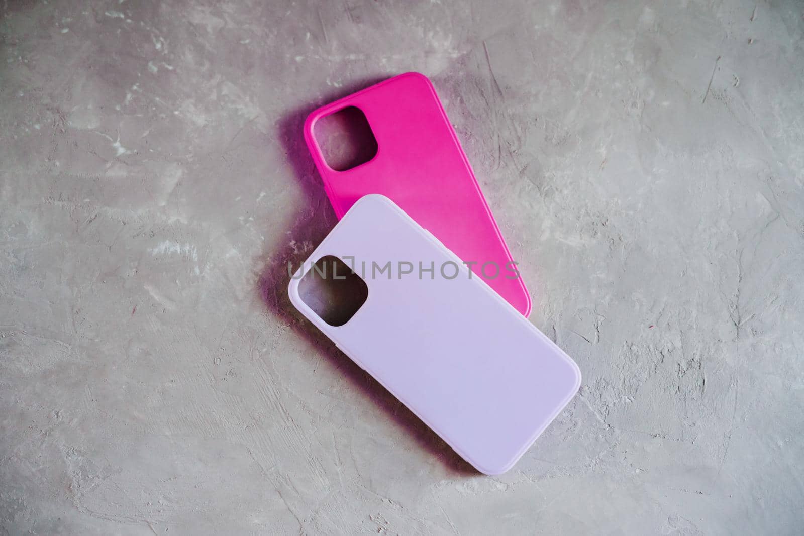 Purple and pink smartphone cases. Two silicone cases on a textured gray background.