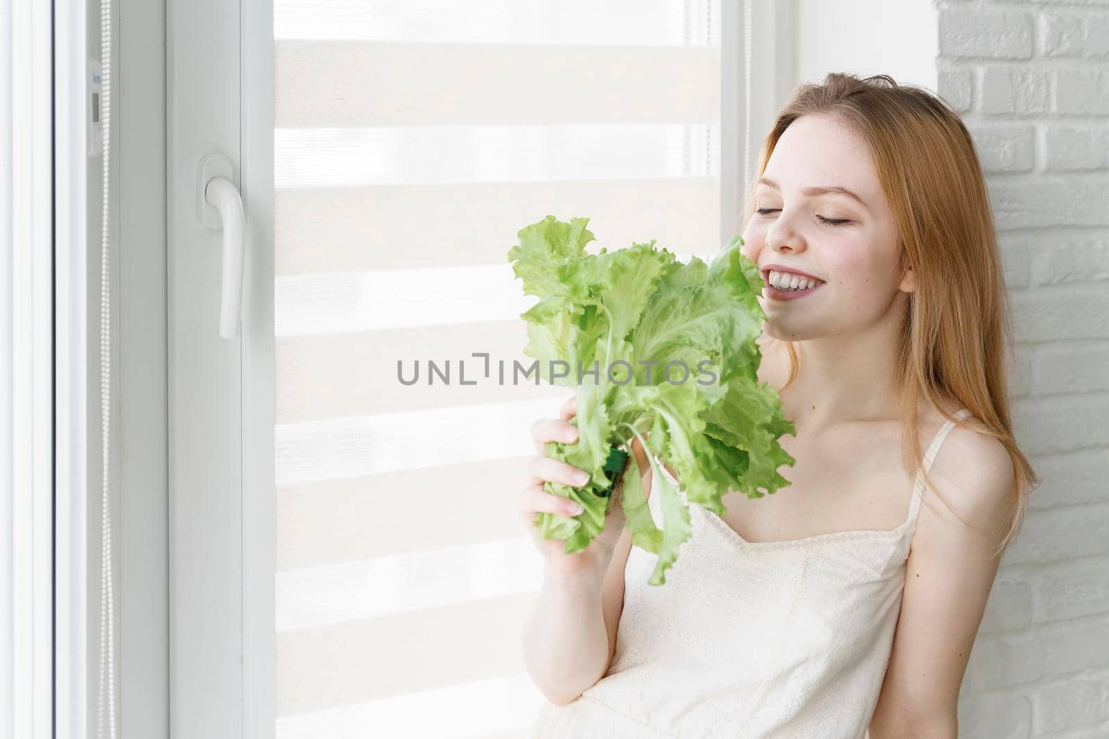 young woman with a bunch of lettuce in a white room. healthy lifestyle, vegetarianism