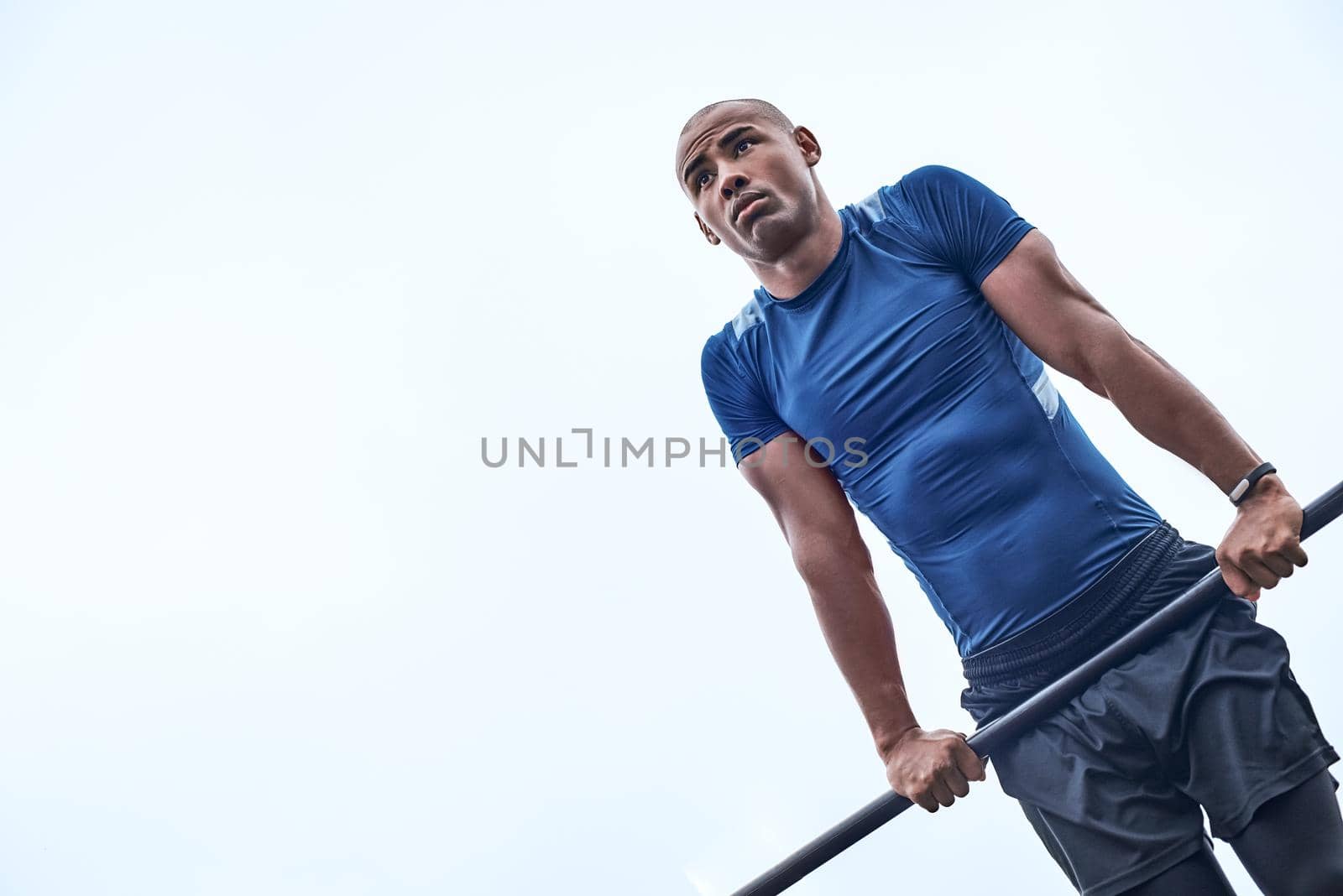 An african man is exercising at open air gym. Close-up photo of black african handsome guy in sports clothes is doing exercises for his hands