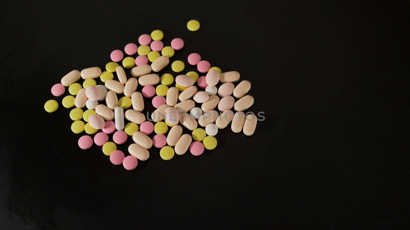 Medicines tablets, capsules, pills of different kinds, sizes and colors, piled up in bulk.Colored vitamin close up. Tablets of different sizes close-up. by Rusrussid