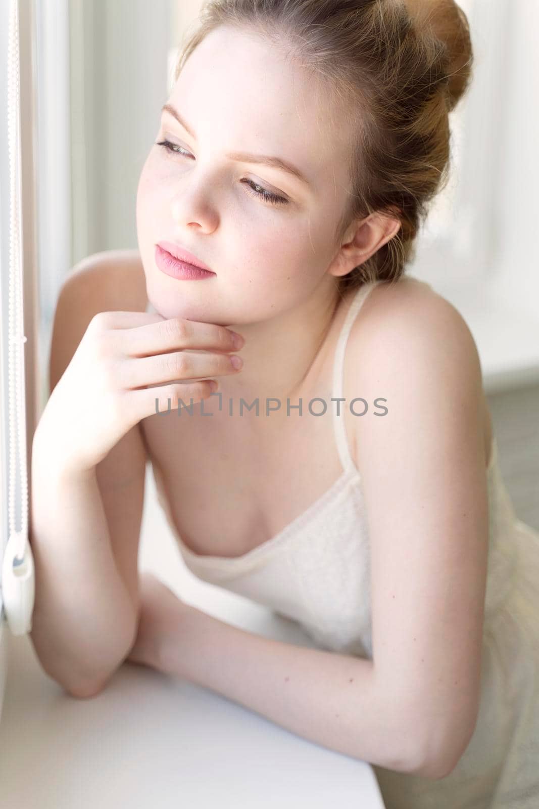 dreamy young caucasian woman by the window.