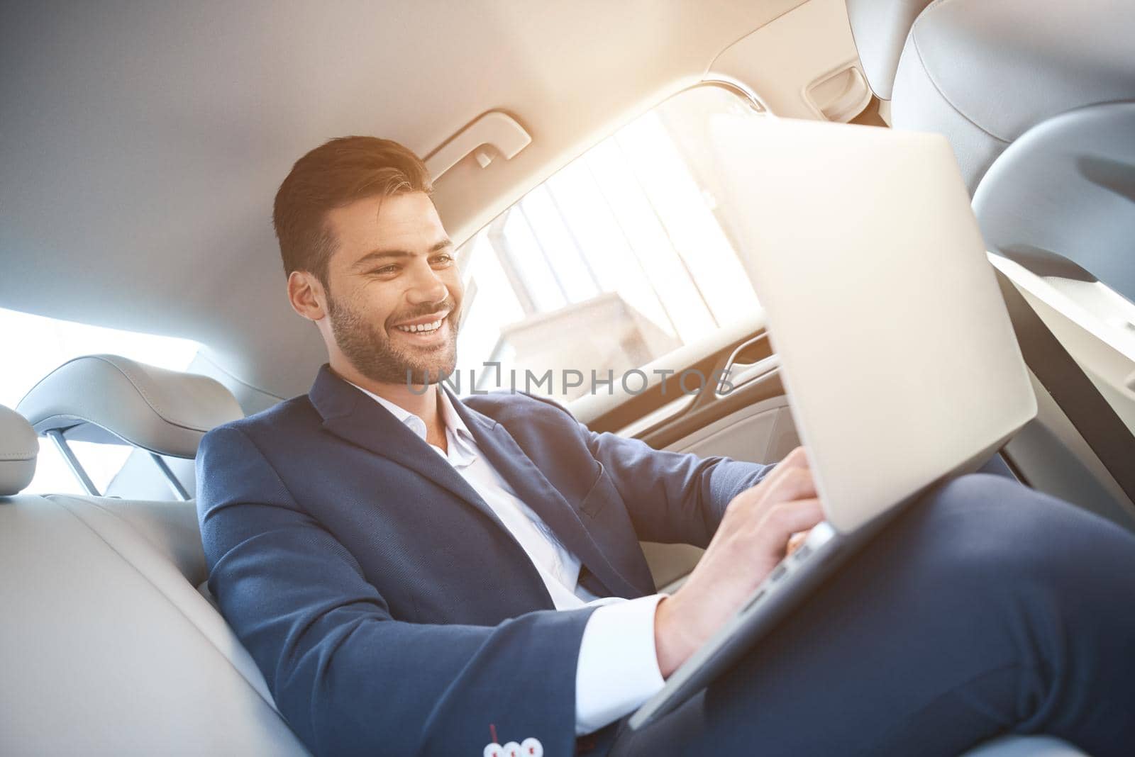 The young man chatting with someone and laughs. On his knees he has a laptop by friendsstock