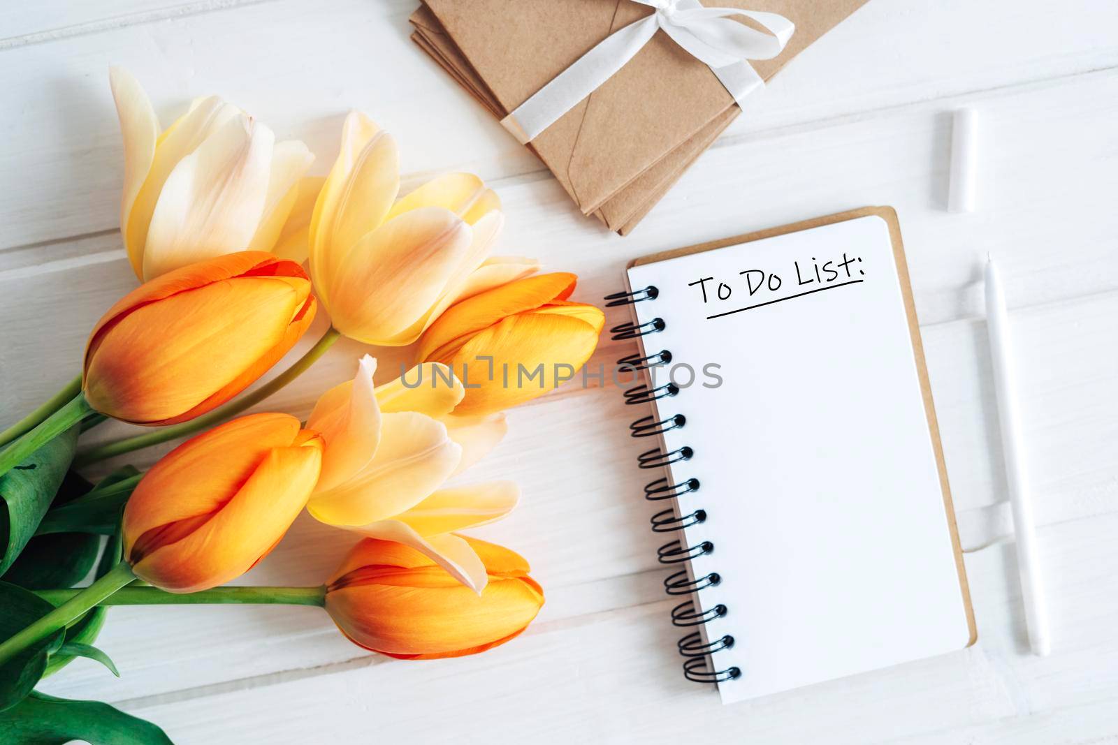 Notebook with a to-do list. A bouquet of bright tulips.