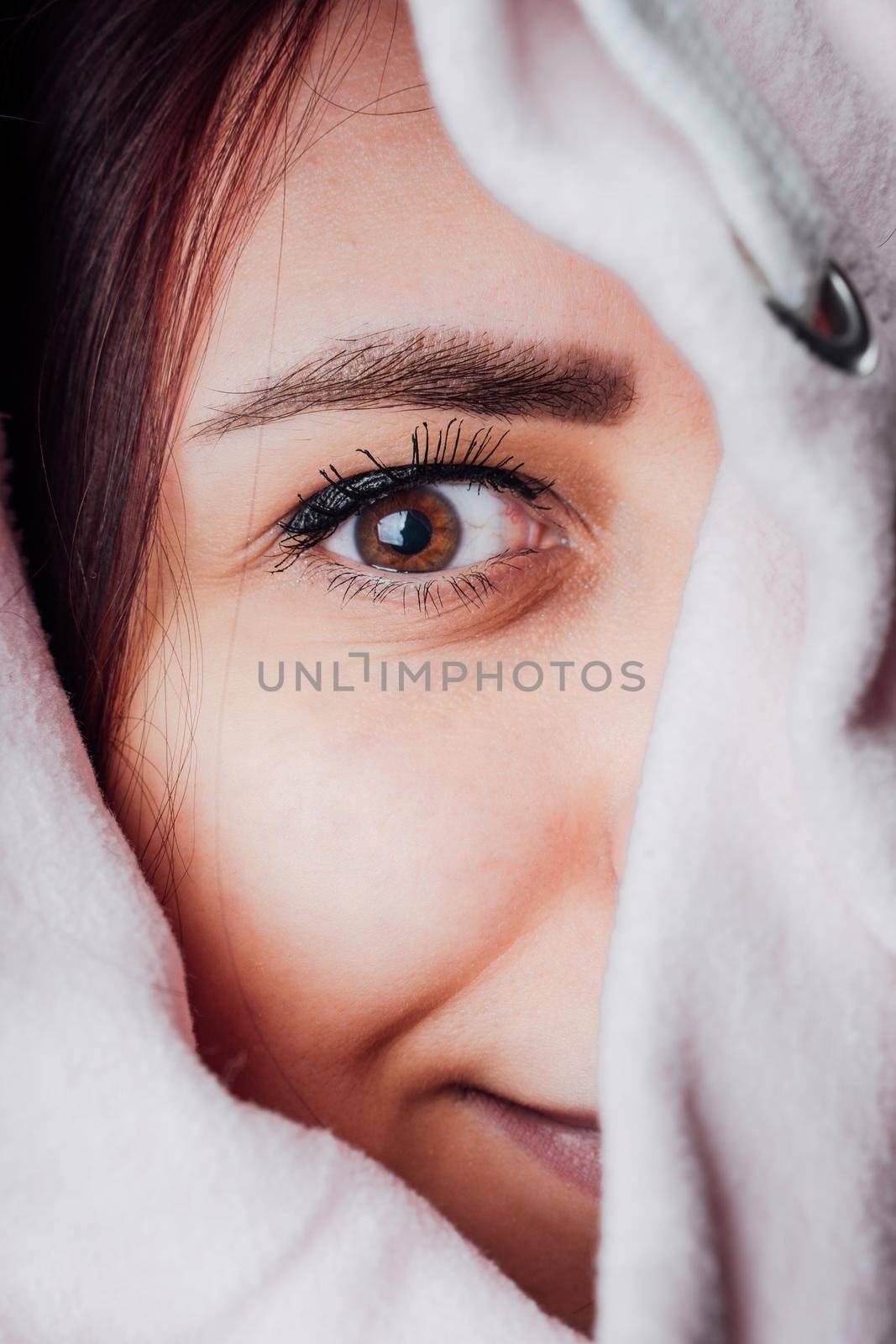 The woman hides her face behind the hood. Stylish female posing in a hoodie. Portrait of a young woman covering her face with a hood.