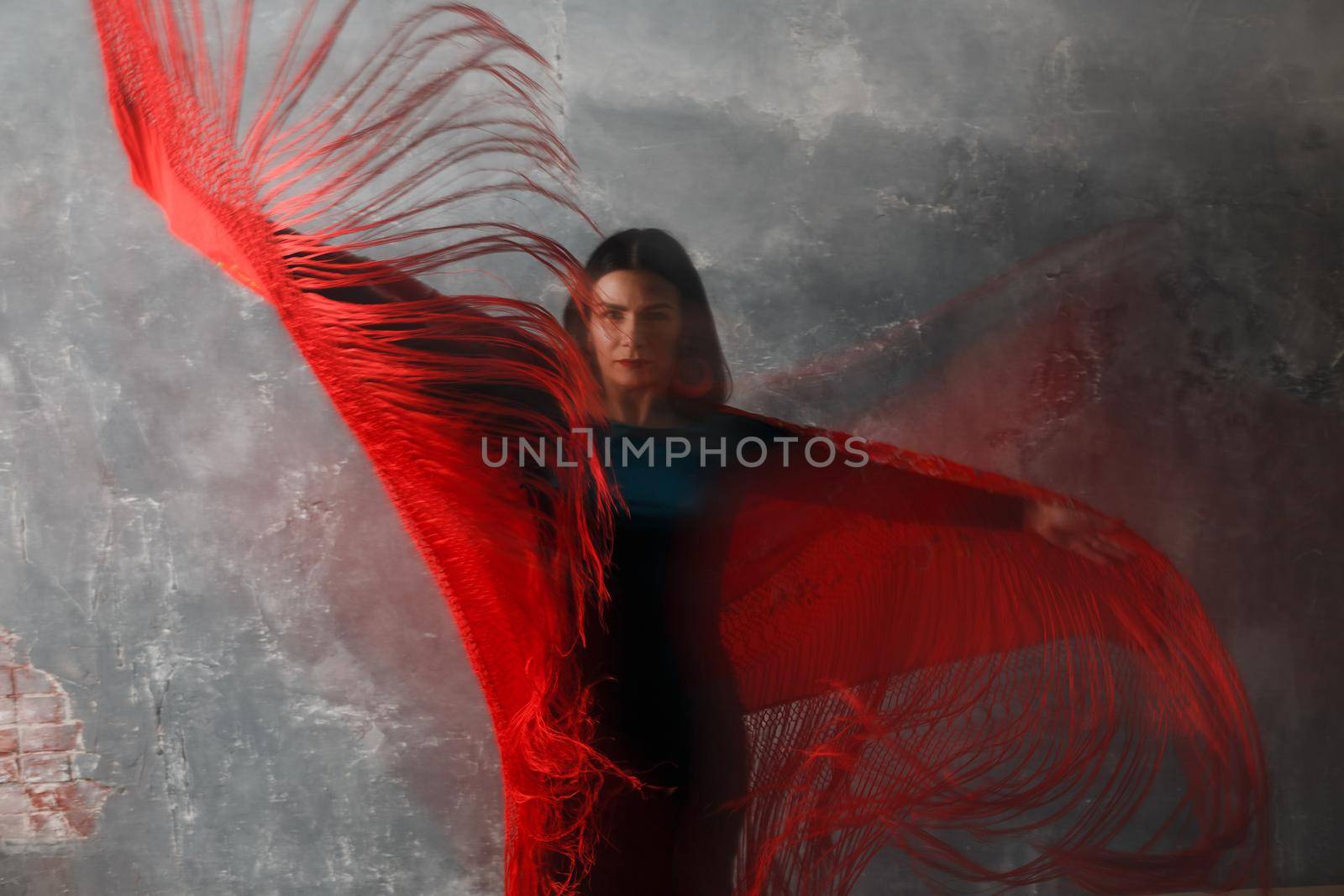 Young adult spanish woman dancing flamenco on gray vintage studio background motion blur
