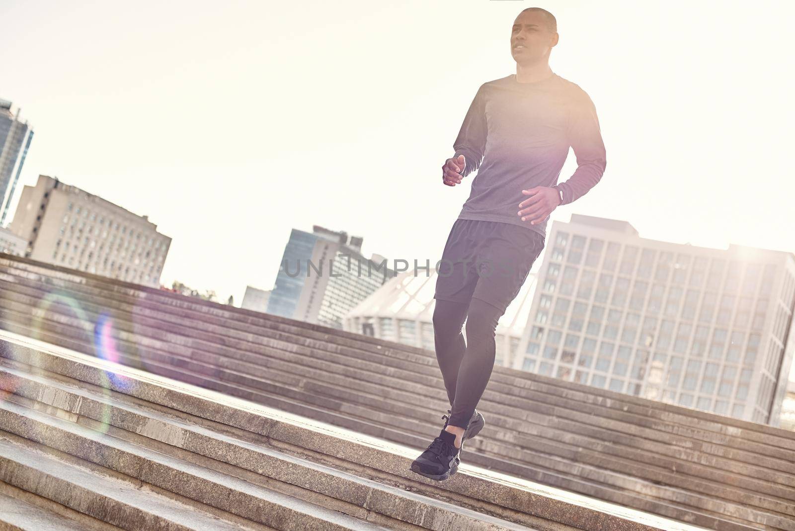 Healthy way of life. Full length portrait of athletic african man in sportswear running down stairs on a sunny warm day. Urban environment. Cardio training. Morning workout. Sport motivation concept. Fitness concept