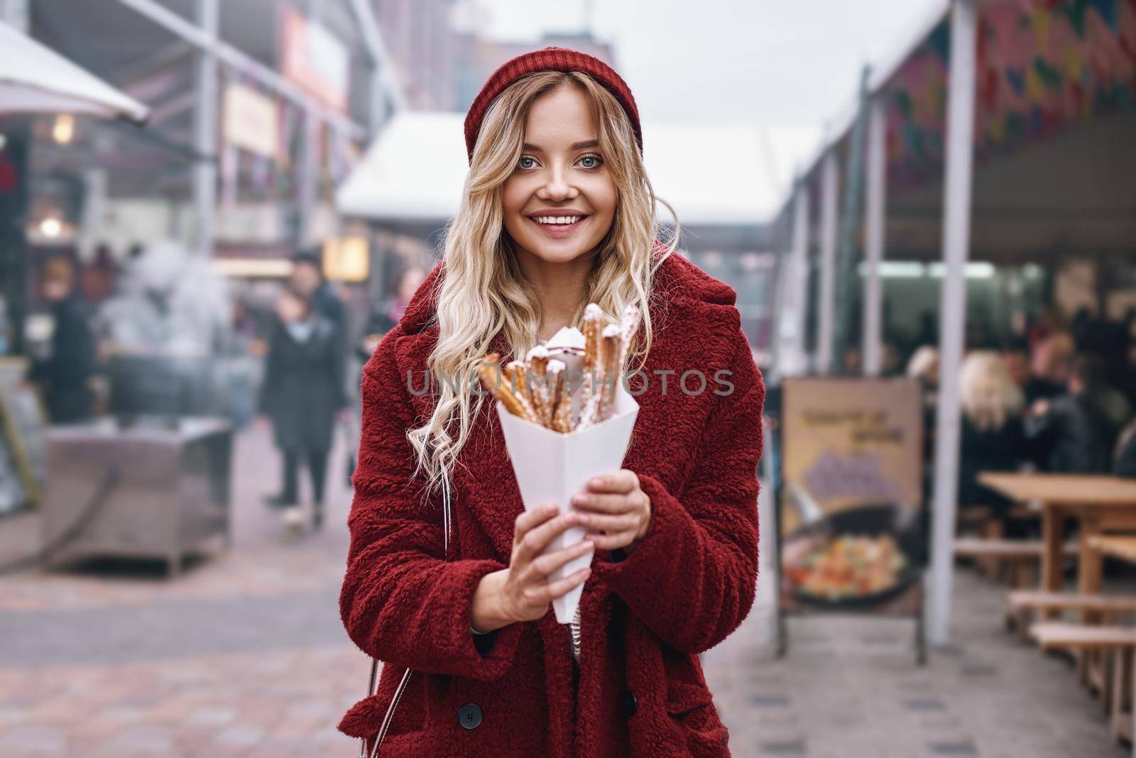 Close-up of young blonde woman eatting churros by friendsstock