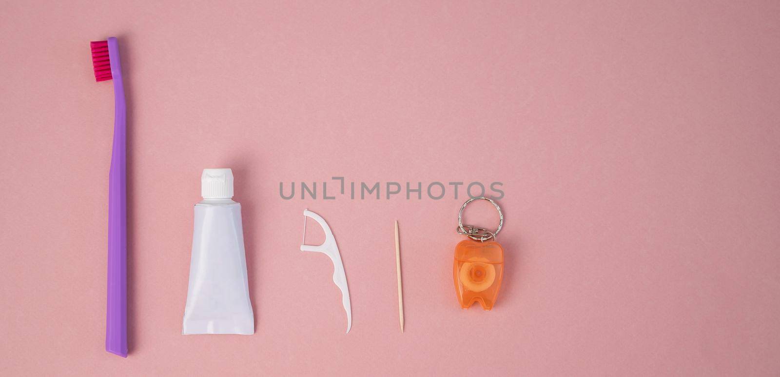 Oral hygiene products on a pink background. Toothbrush toothpaste dental floss and toothpick. Copy space. by mrwed54