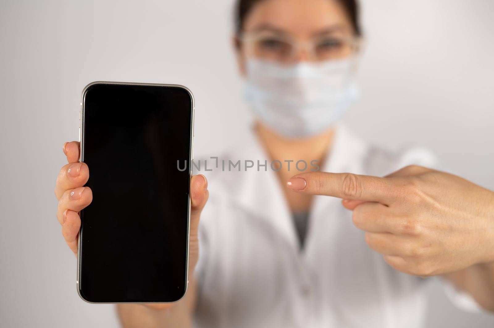 The doctor holds a smartphone with a black screen on a white background