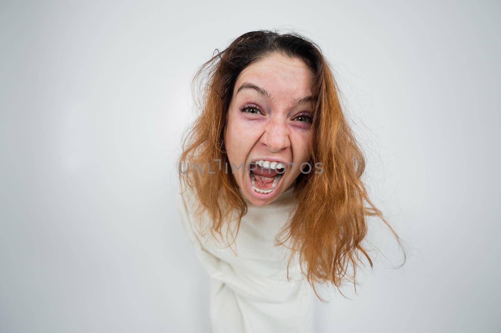 Close-up portrait of insane woman in straitjacket on white background
