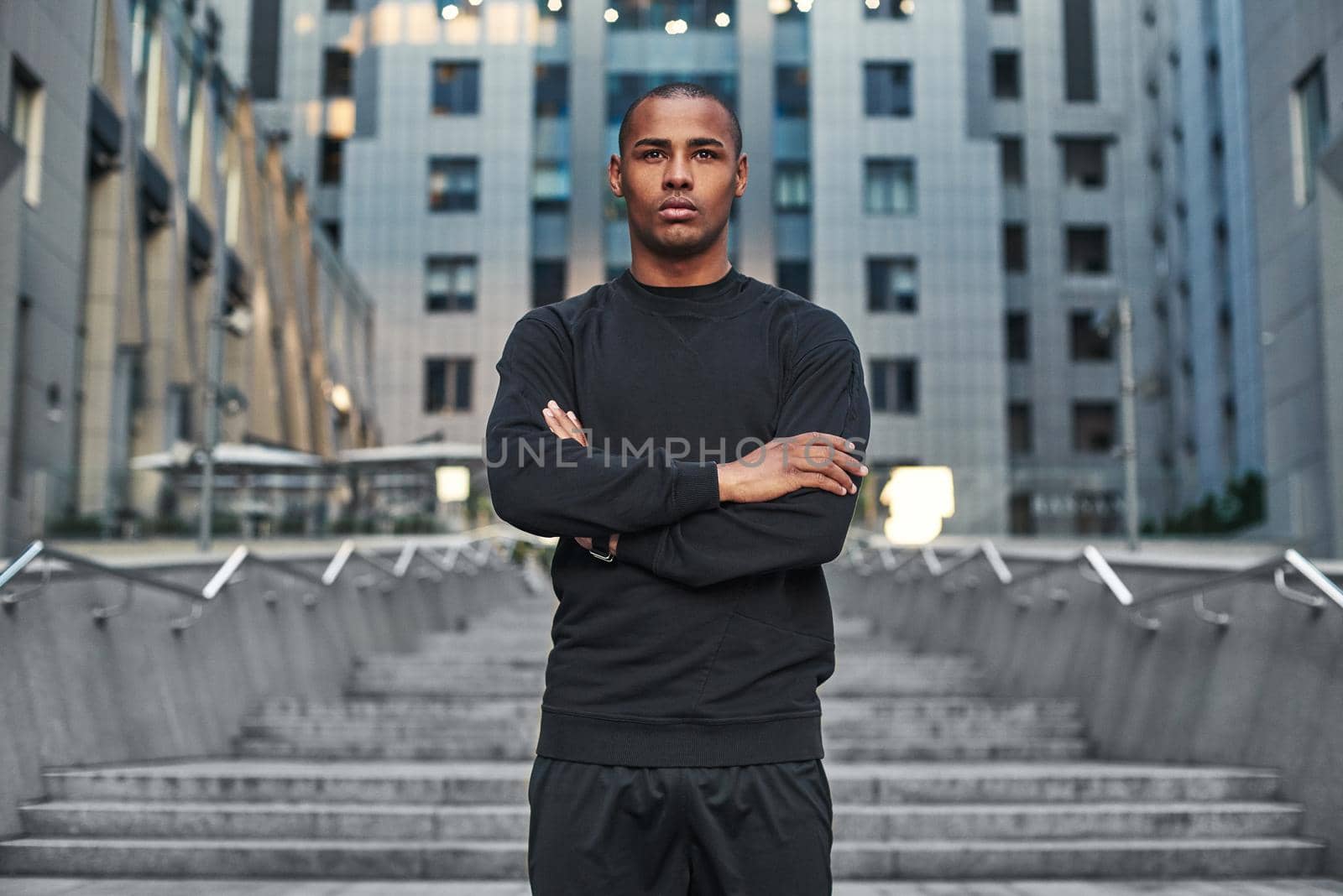 Sport is the way of life. Athletic african man with a muscular body standing on stairs with crossed arms and ready to start his morning workout. Sport concept. Health concept. Lifestyle. Urban workout