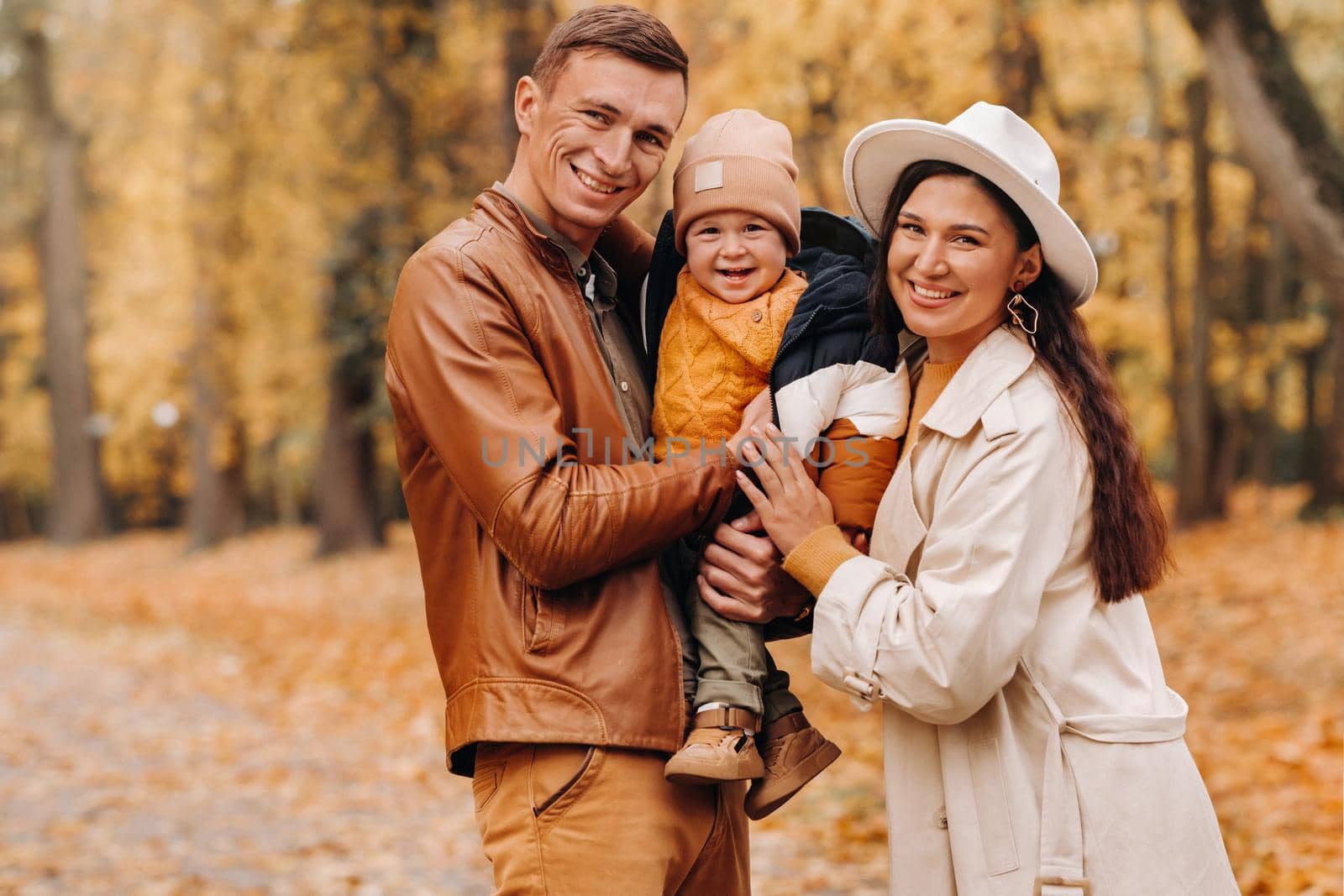 Father and mother with son walking in the autumn Park. A family walks in the Golden autumn in a nature Park