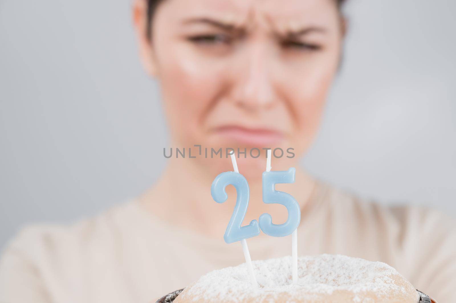 The unhappy woman is holding a cake with candles for her 25th birthday. The girl is crying on her anniversary. Copy space by mrwed54