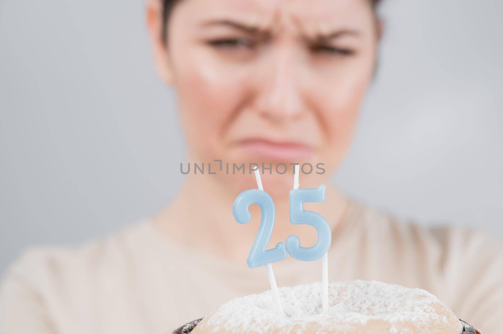 The unhappy woman is holding a cake with candles for her 25th birthday. The girl is crying on her anniversary. Copy space.