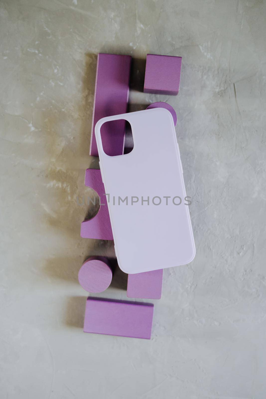 Silicone case of purple color lies on voluminous wooden purple details. Gray textured background.