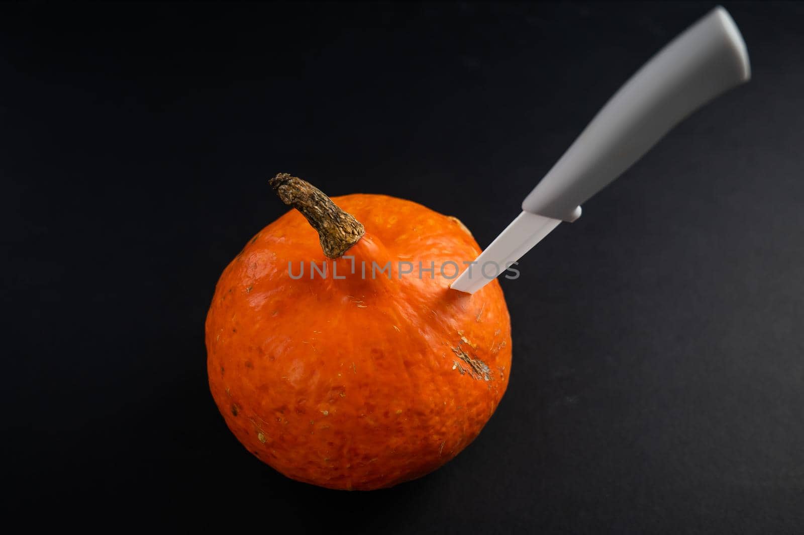 Knife in a pumpkin on a black background. Halloween symbol. Isolate. by mrwed54