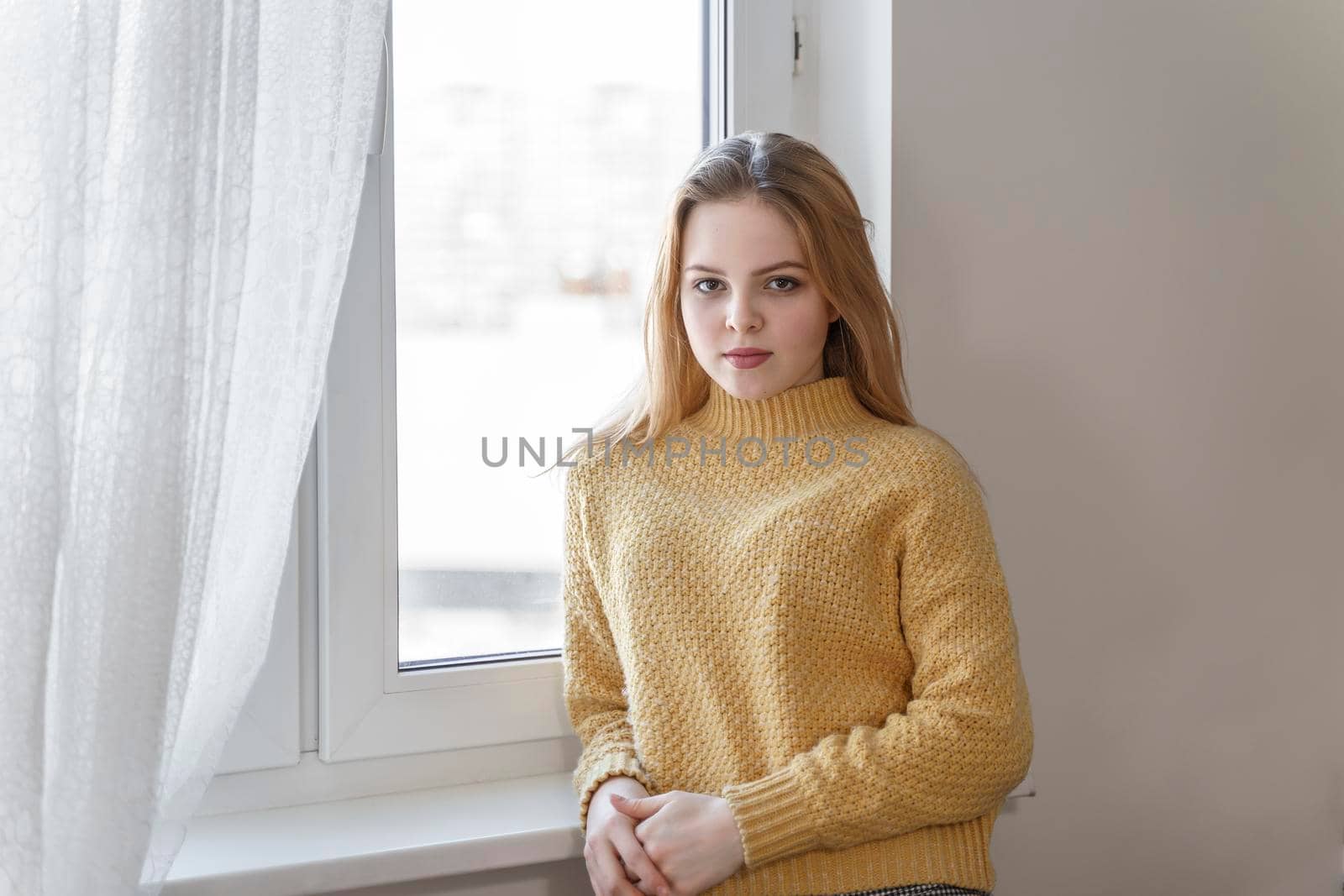 portrait of a teenage girl in a yellow sweater standing by the window by Lena_Ogurtsova