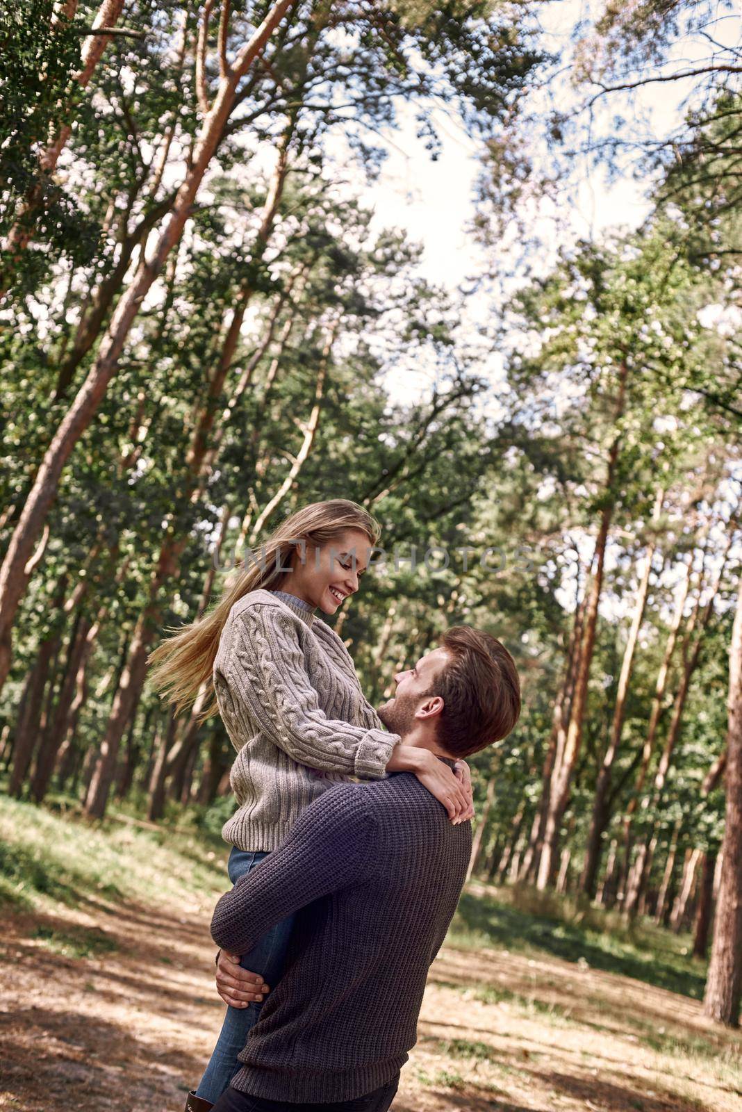 Young man holding his girlfriend on hands in autumn forest. by friendsstock