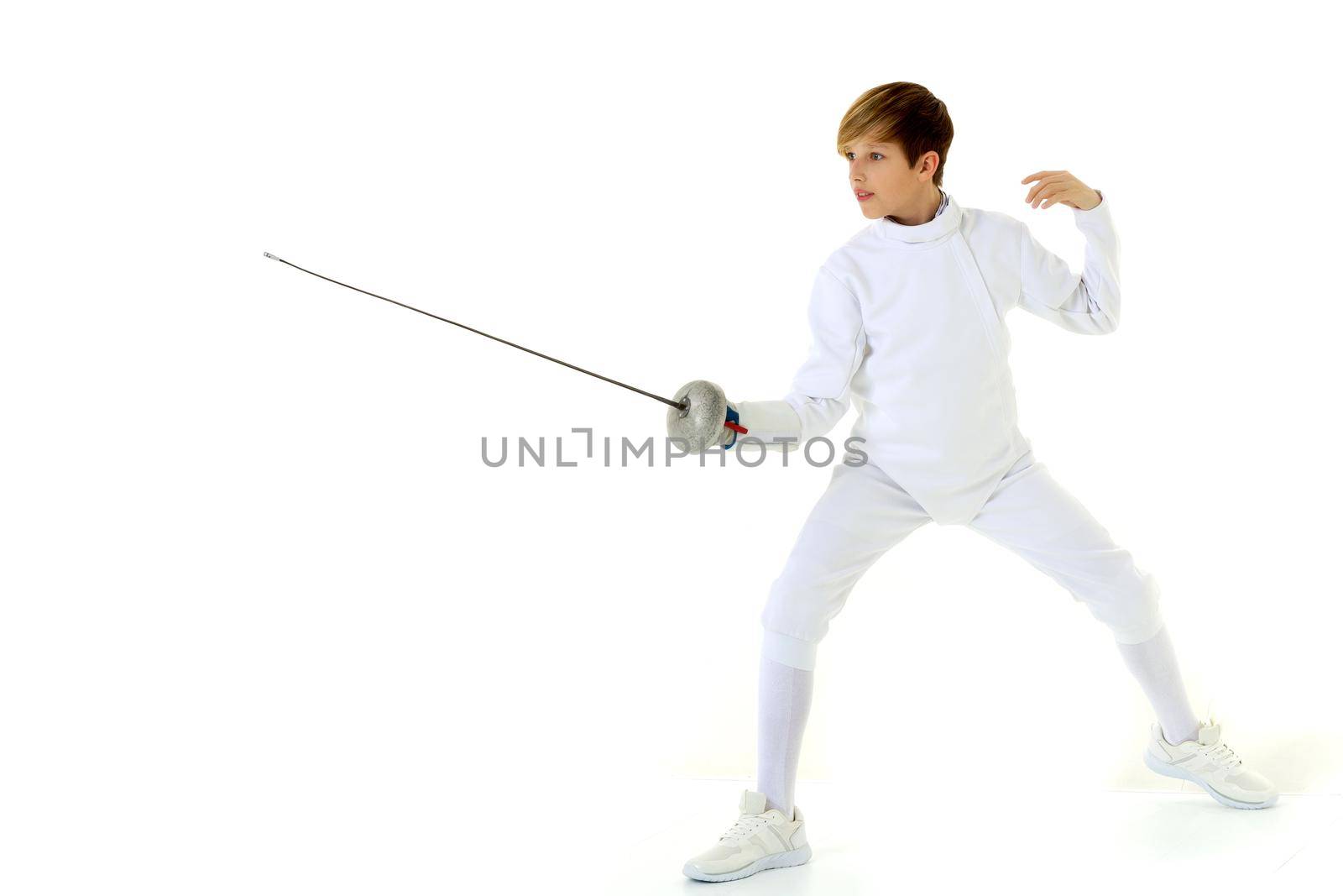 Boy fencer standing in attacking pose. Junior boy wearing white fencing suit posing with rapier against white background. Teenager practicing in fencing or taking part at tournament