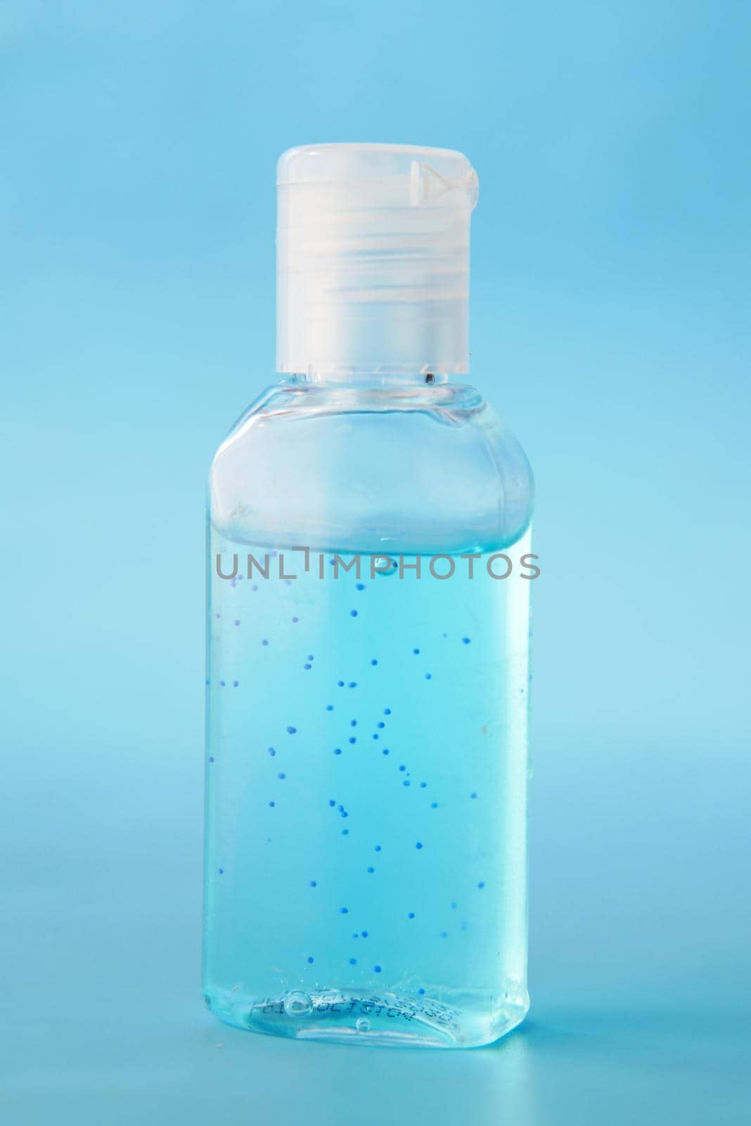 transparent hand sanitizer liquid in a container on blue backgorund .