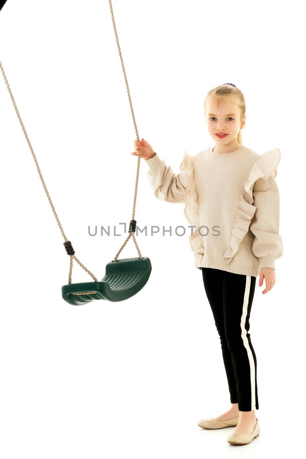 Cute little girl is standing near the swing. by kolesnikov_studio