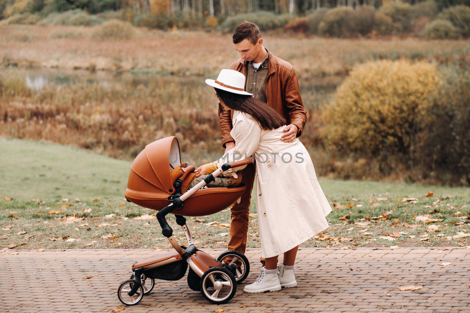 Father and mother on a walk with a stroller in the autumn Park. The family walks through the nature Park in the Golden autumn