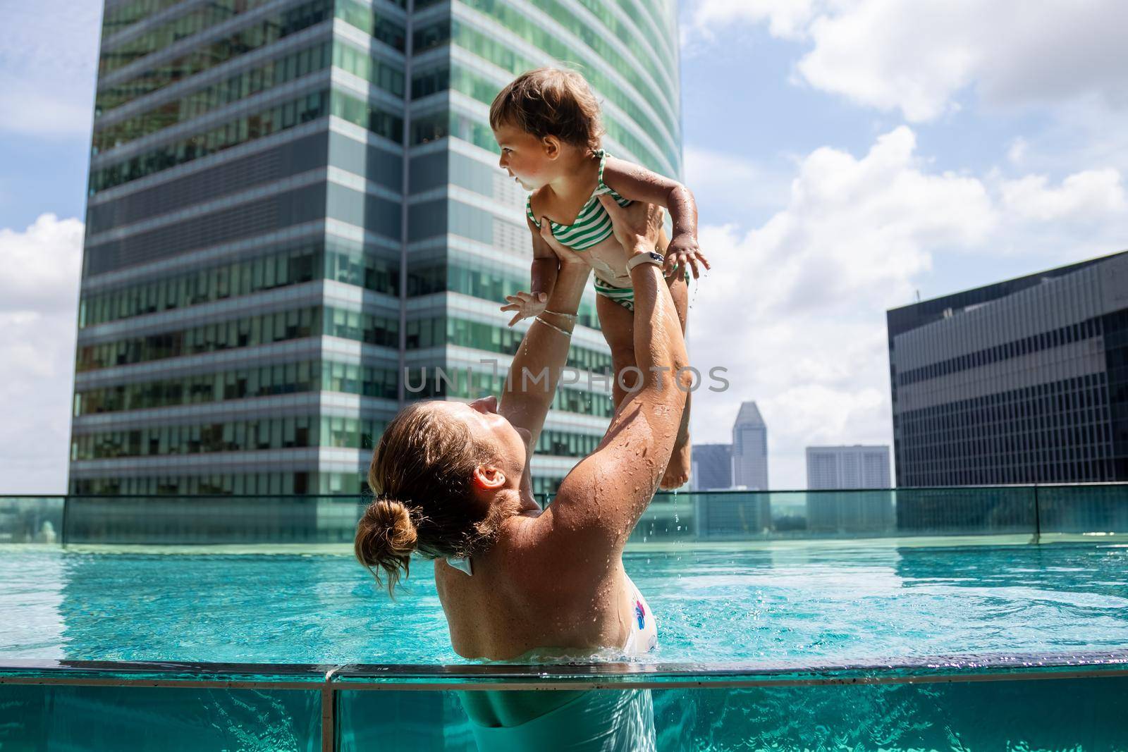 young woman playing in the pool with little toddler girl..