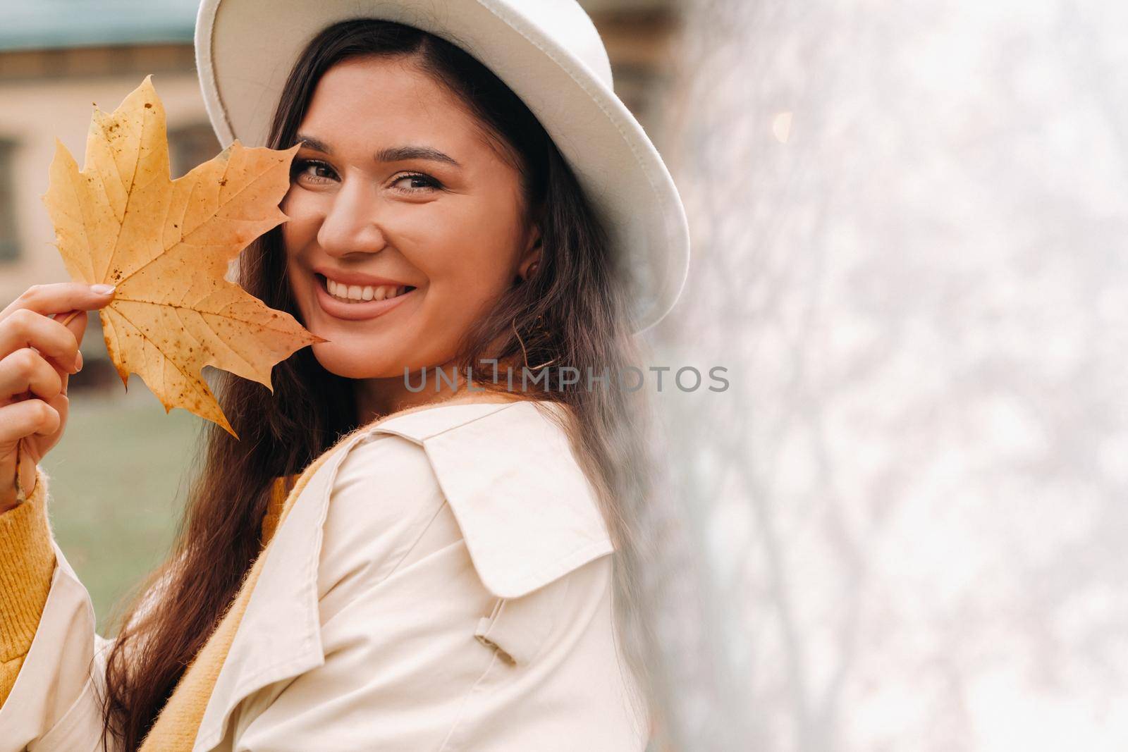 a girl in a white coat and hat smiles in an autumn Park.Portrait of a woman in Golden autumn. by Lobachad