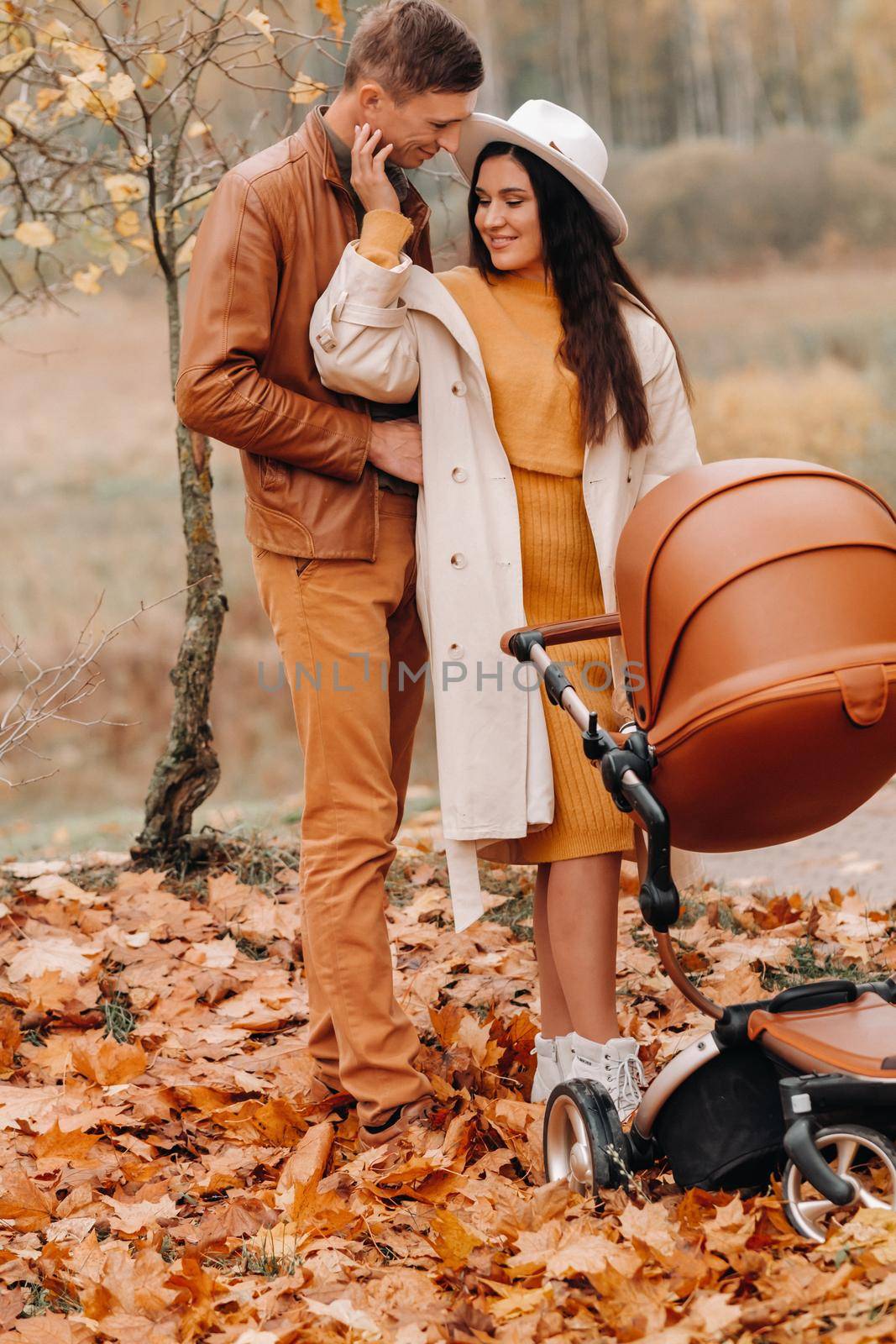 Father and mother on a walk with a stroller in the autumn Park. The family walks through the nature Park in the Golden autumn