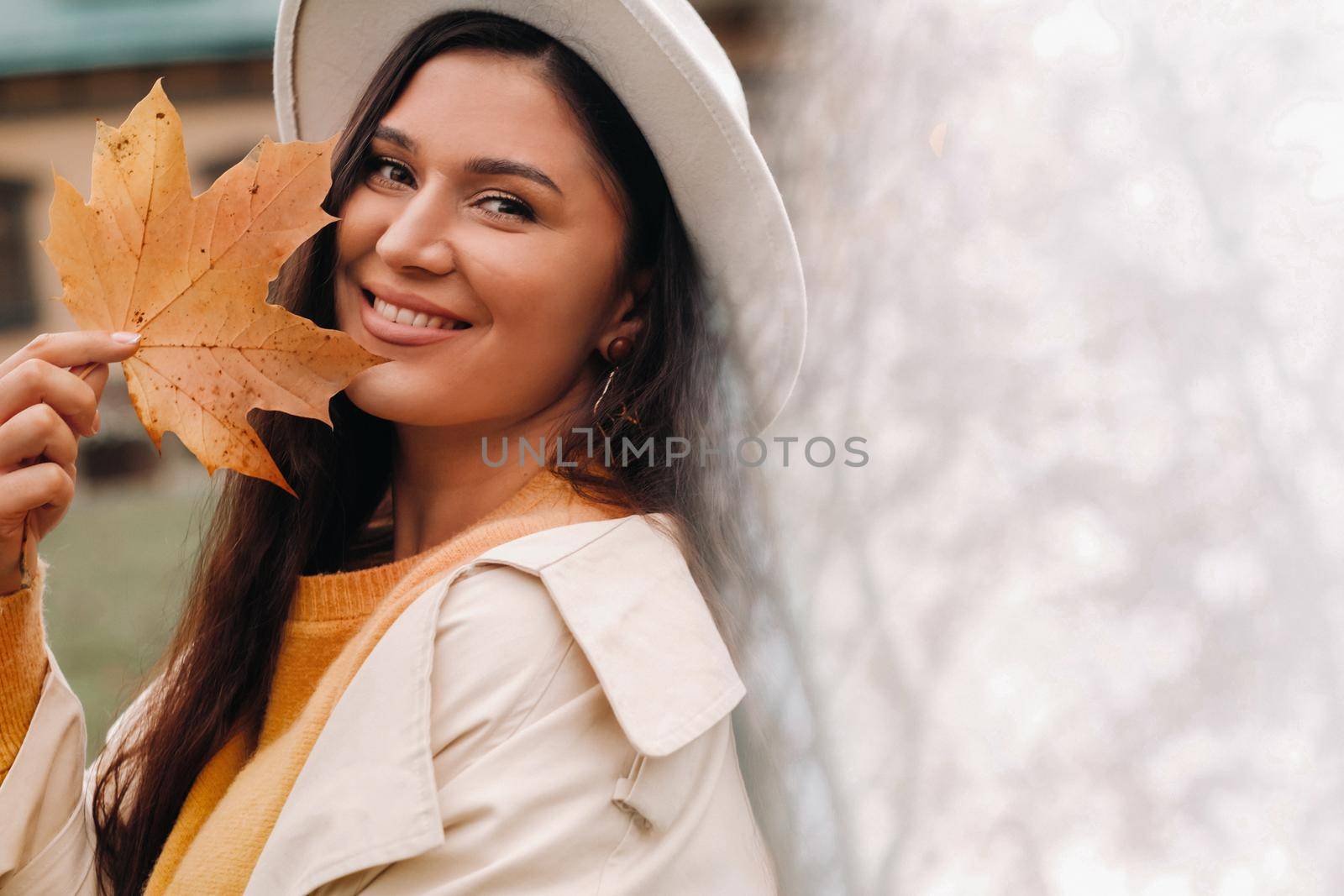a girl in a white coat and hat smiles in an autumn Park.Portrait of a woman in Golden autumn