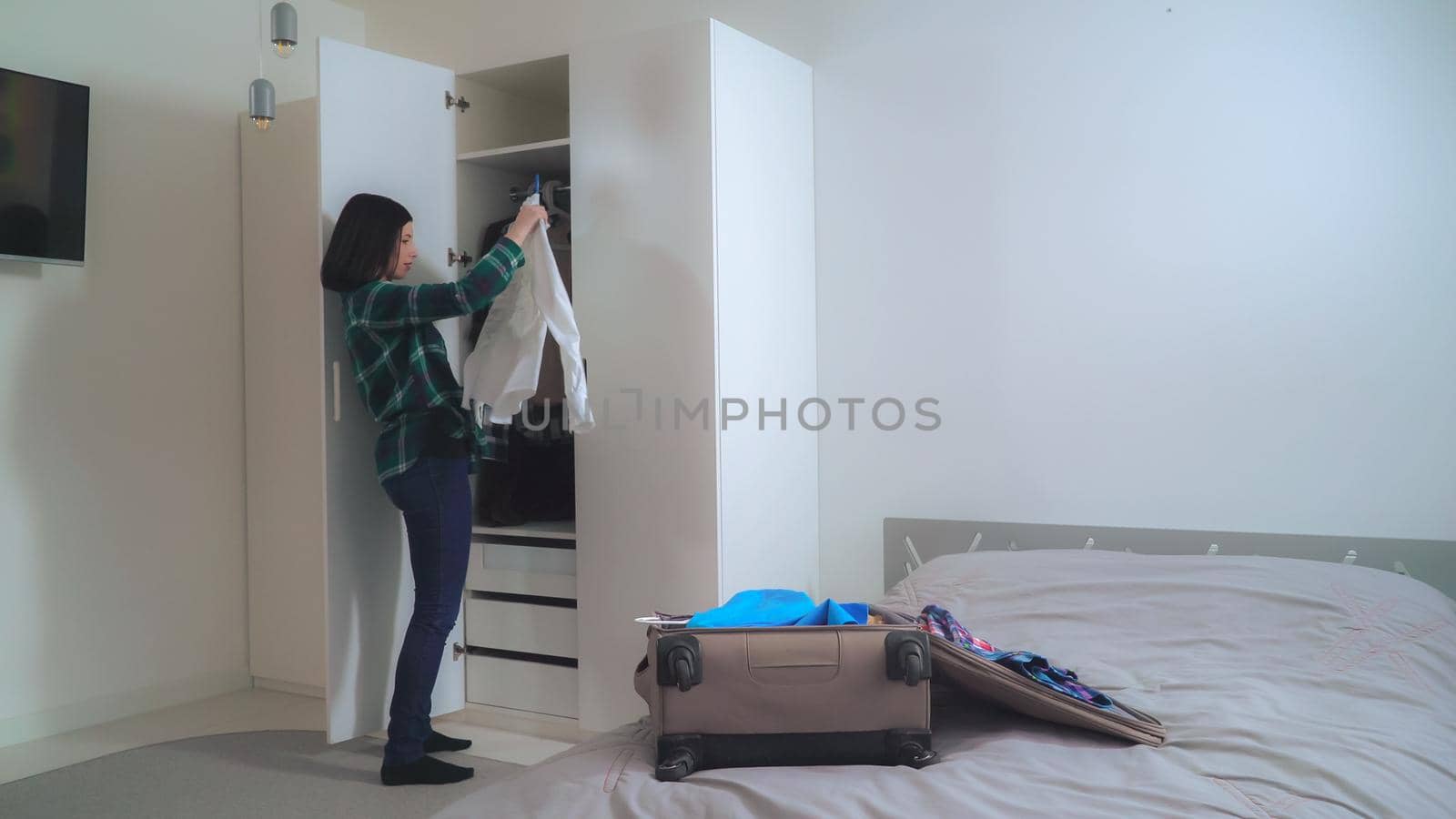 Girl putting dress in bag in bedroom. by VadosLoginov