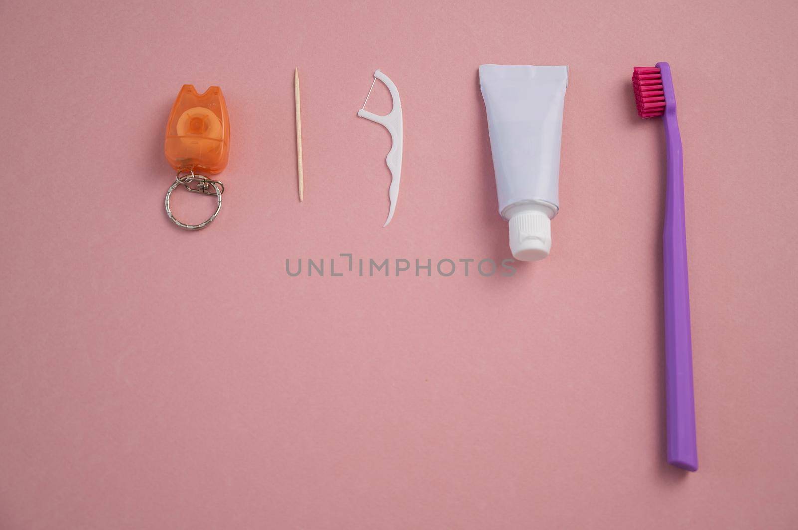 Oral hygiene products on a pink background. Toothbrush toothpaste dental floss and toothpick. Copy space. by mrwed54