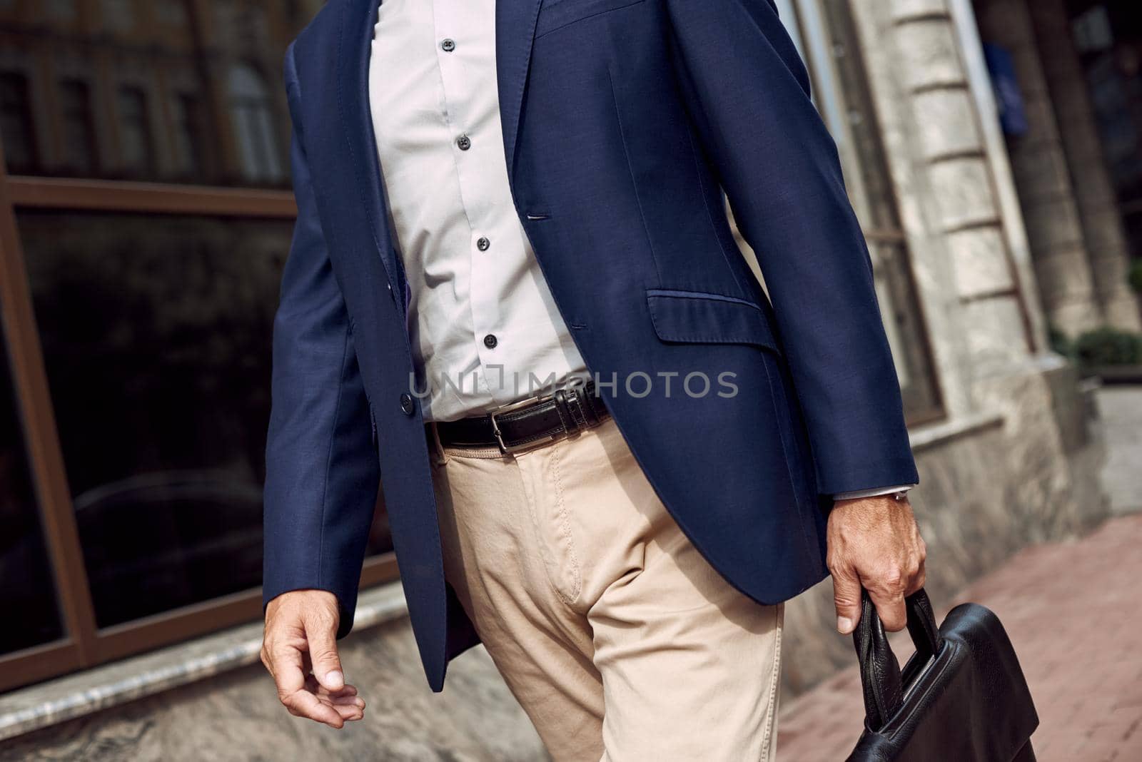 Think through a business meeting. Elegant man in casual suit smiling while walking outdoors