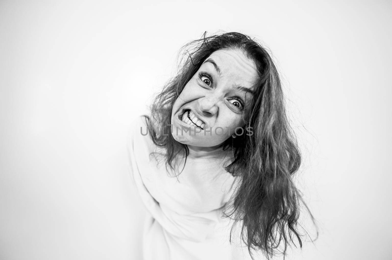 Close-up portrait of insane woman in straitjacket on white background. Monochrome. by mrwed54