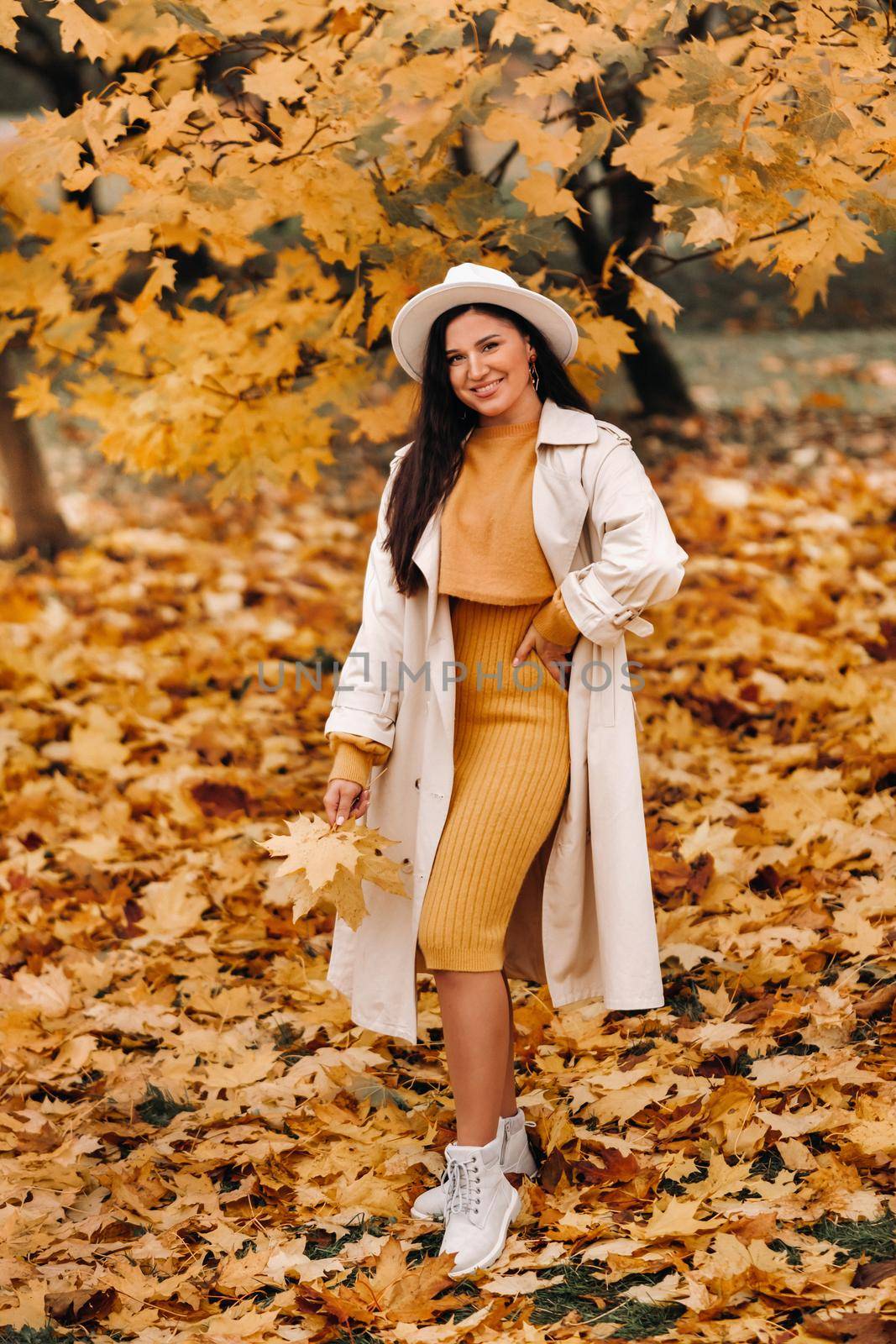 a girl in a white coat and hat smiles in an autumn Park.Portrait of a woman in Golden autumn