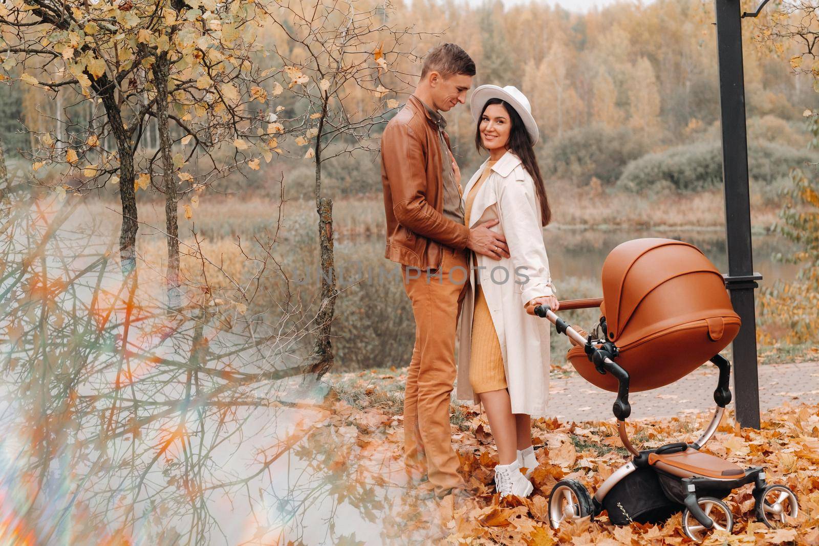 Father and mother on a walk with a stroller in the autumn Park. The family walks through the nature Park in the Golden autumn