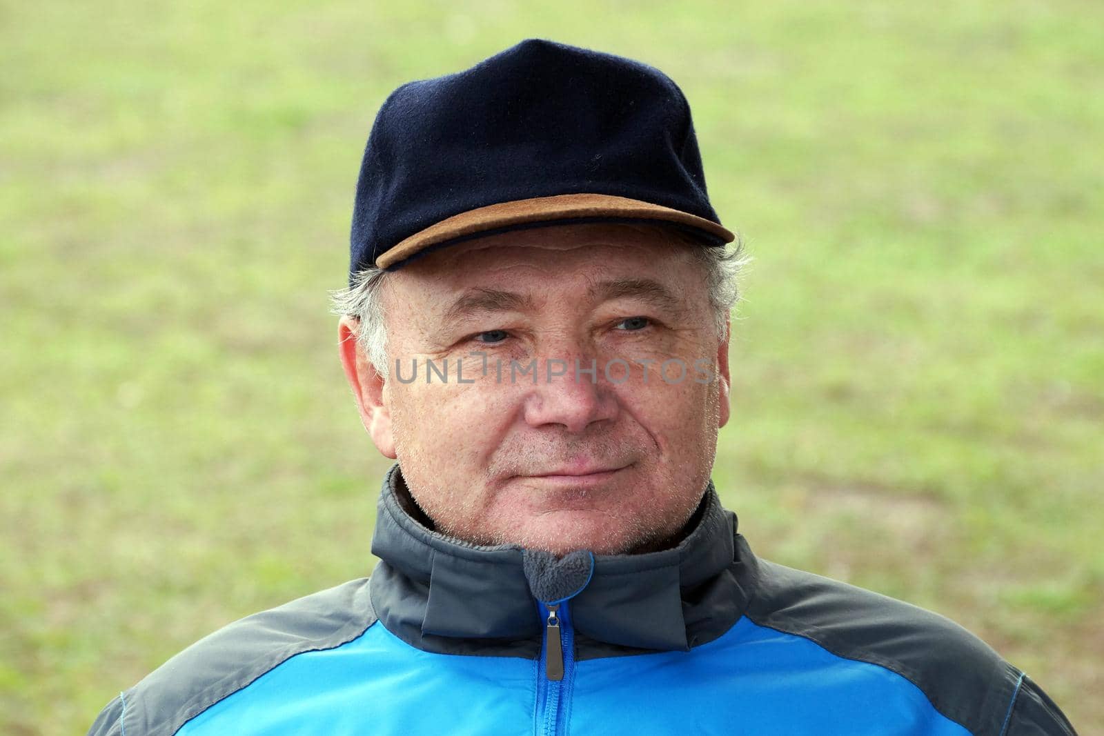 portrait of a smiling middle aged man in a cap on a natural background