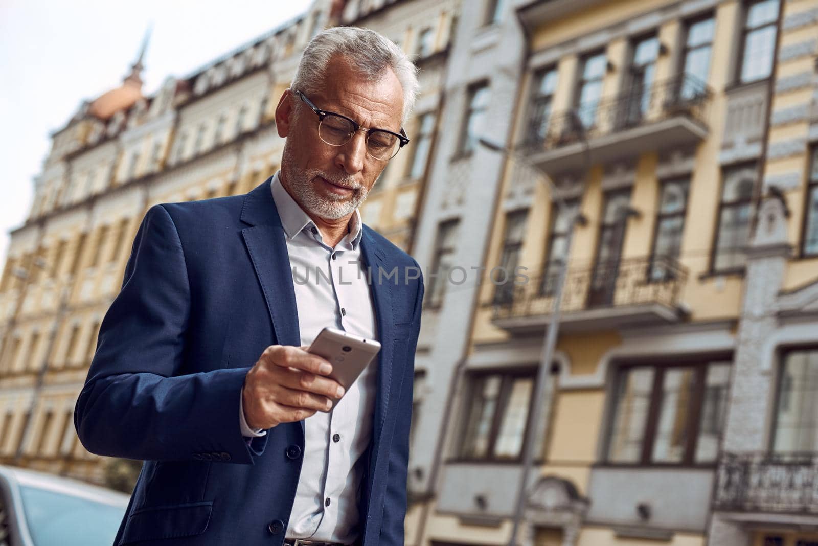 Business texting. Serious young businessman using mobile phone for work