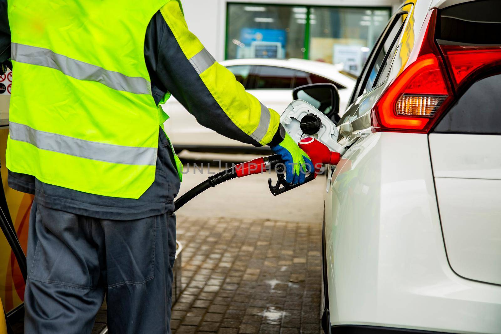 gas station employee in overalls refueling the car with petrol close up. no face