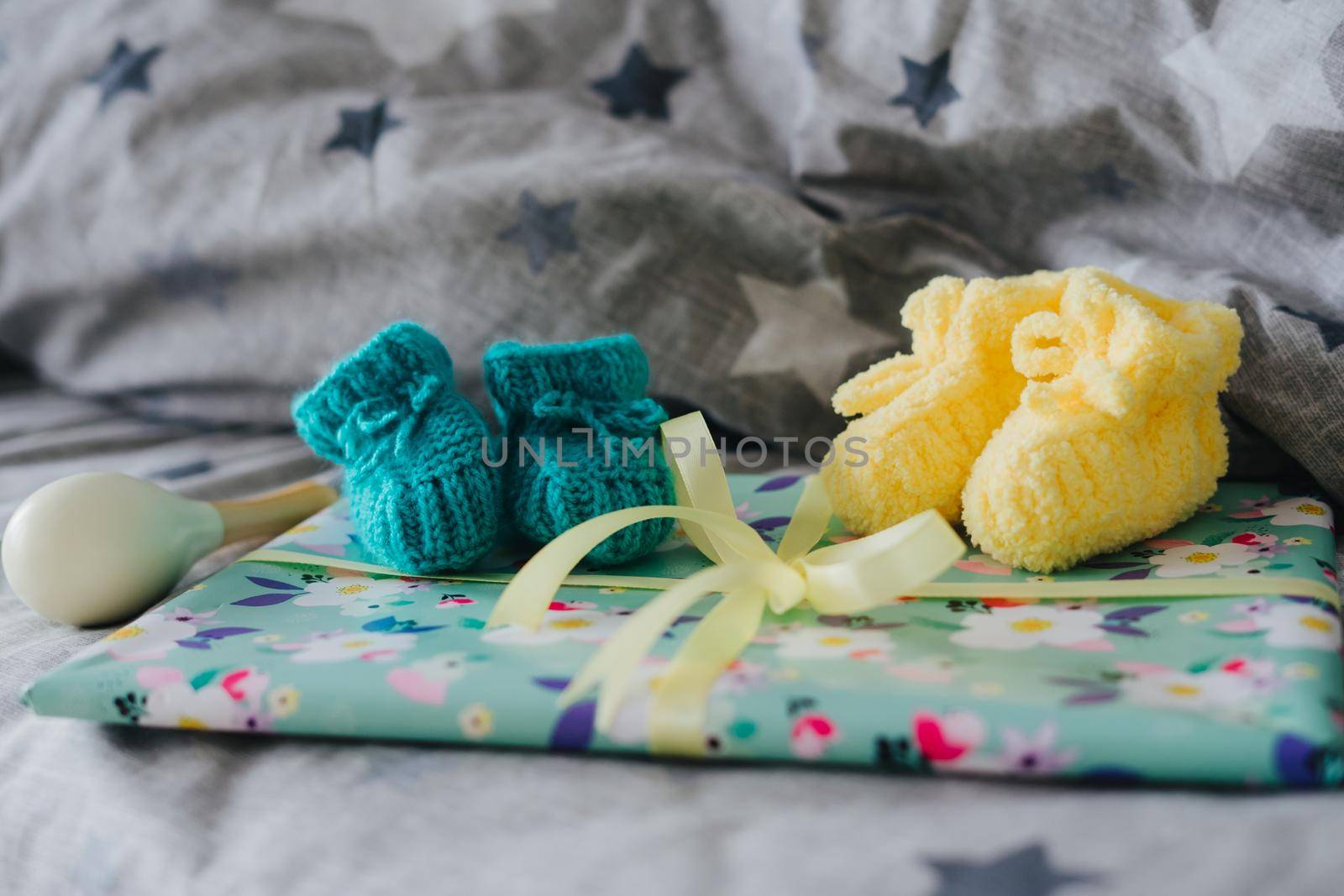 Knitted booties for a small child and a gift tied with a ribbon. by Rodnova