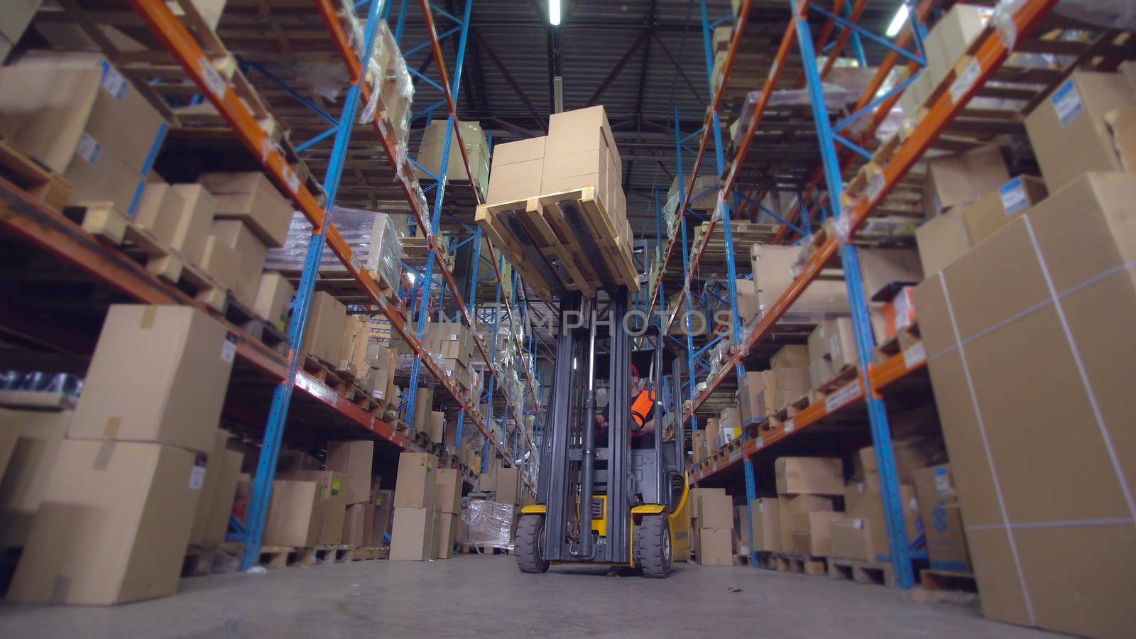 forklift operator puts boxes with goods on the metal racks