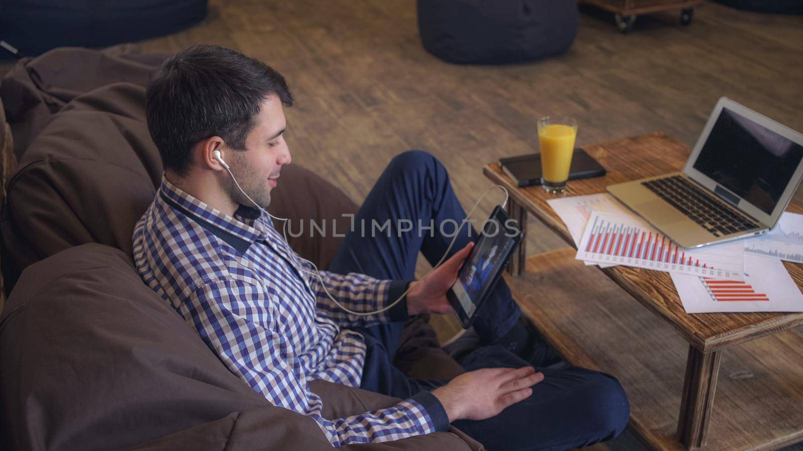Attractive man holding tablet in hand, headphones dressed, online conference. by VadosLoginov