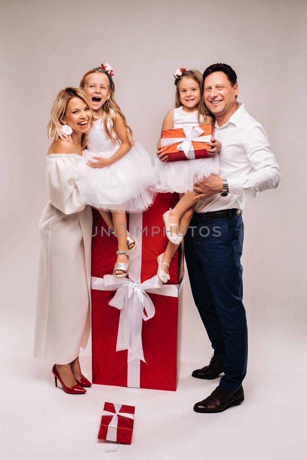 Portrait of a happy family with gifts in their hands on a beige background.