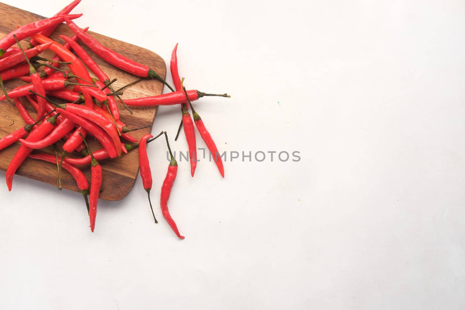 top view of red chili on a chopping board on white .