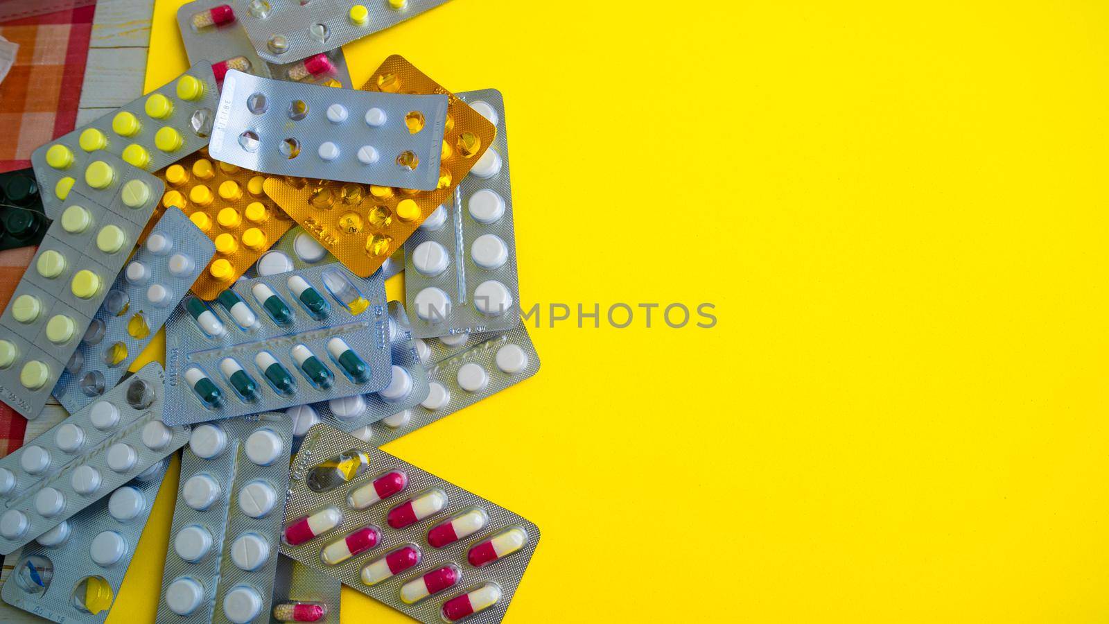 Close up of medical blister packs with tablets on yellow background. Packs with various tablets. Concept of threat of various diseases. by epidemiks