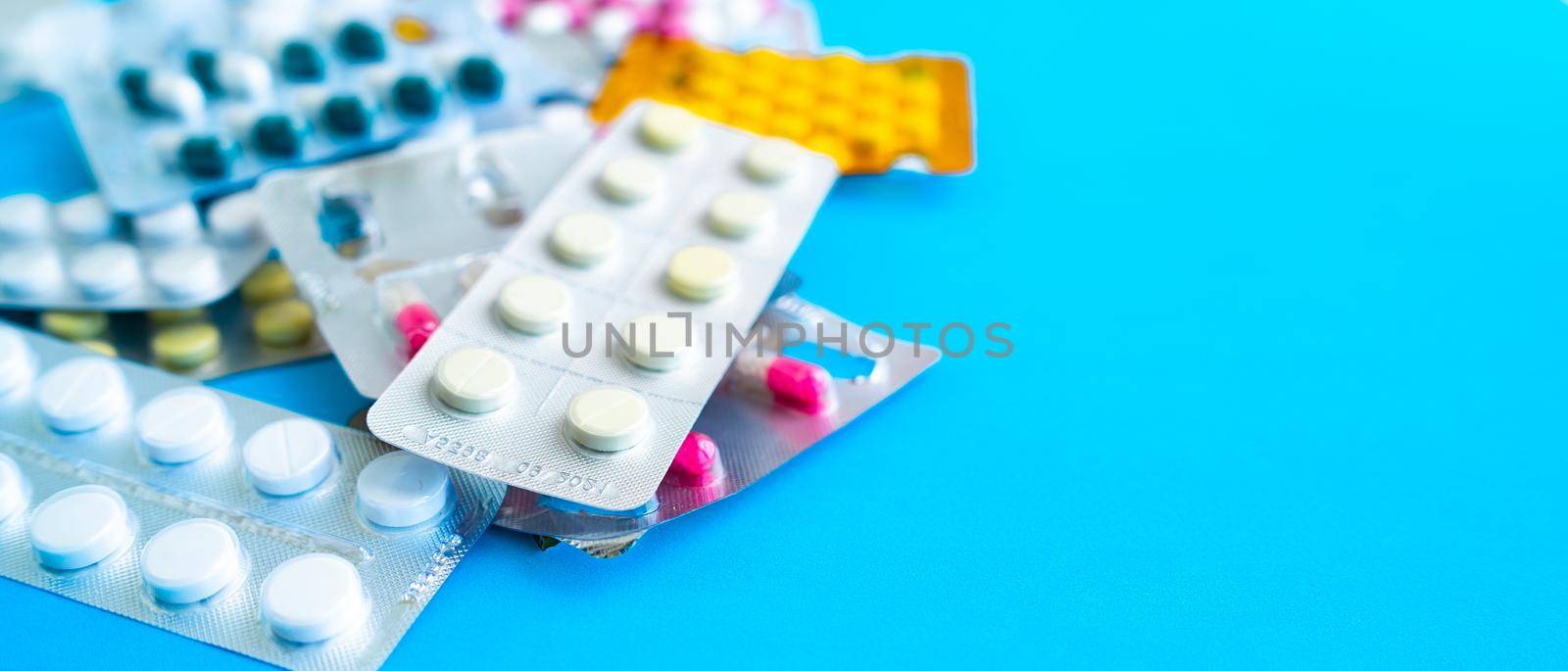 Close up of medical blister packs with tablets on blue background. Packs with various tablets. Concept of threat of various diseases