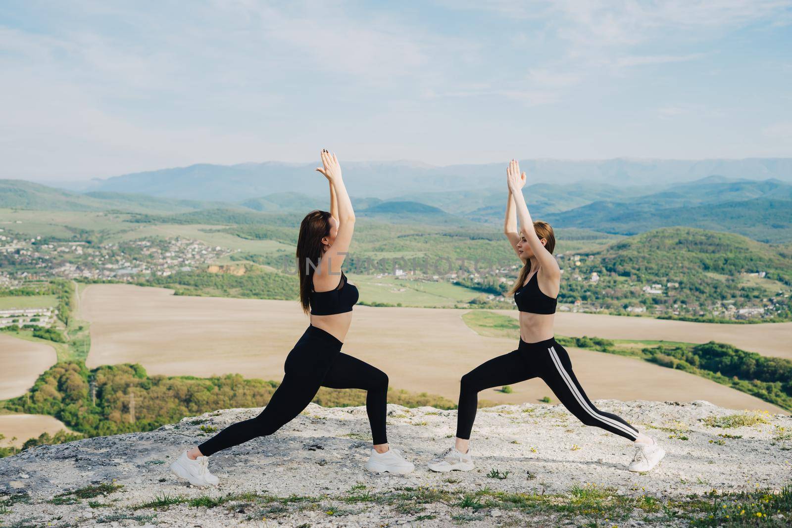 Two girls play sports on a cliff. Yoga in nature. A healthy lifestyle.