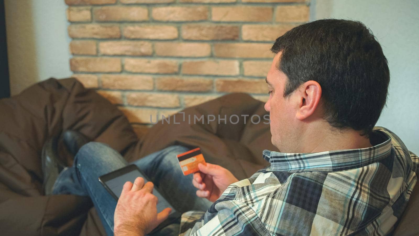 The man using digital tablet for pay online. Holding in the hands credit card