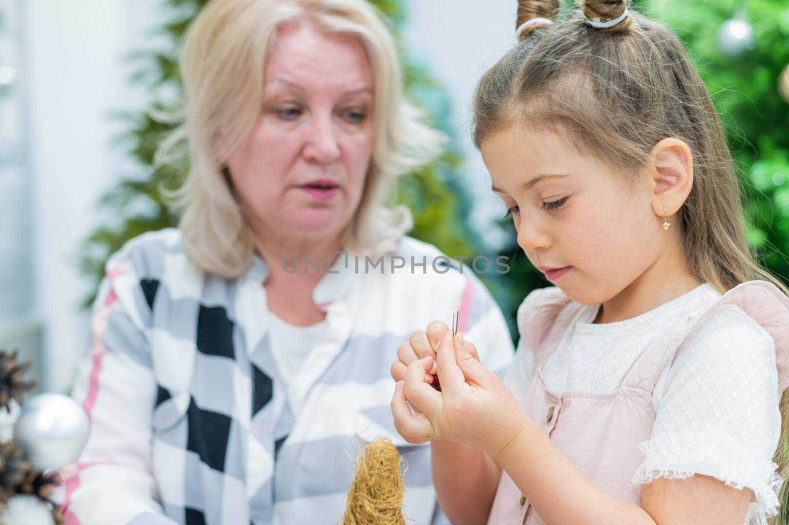 Elderly caucasian woman making pine cones decoration for christmas with two granddaughters by mrwed54