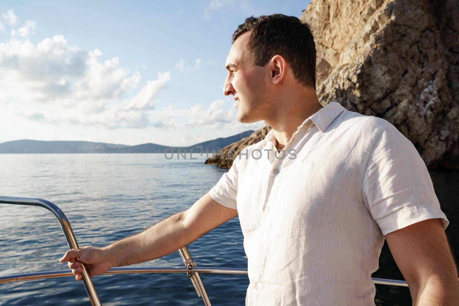 Young man in white shirt standing on the nose yacht in the open sea